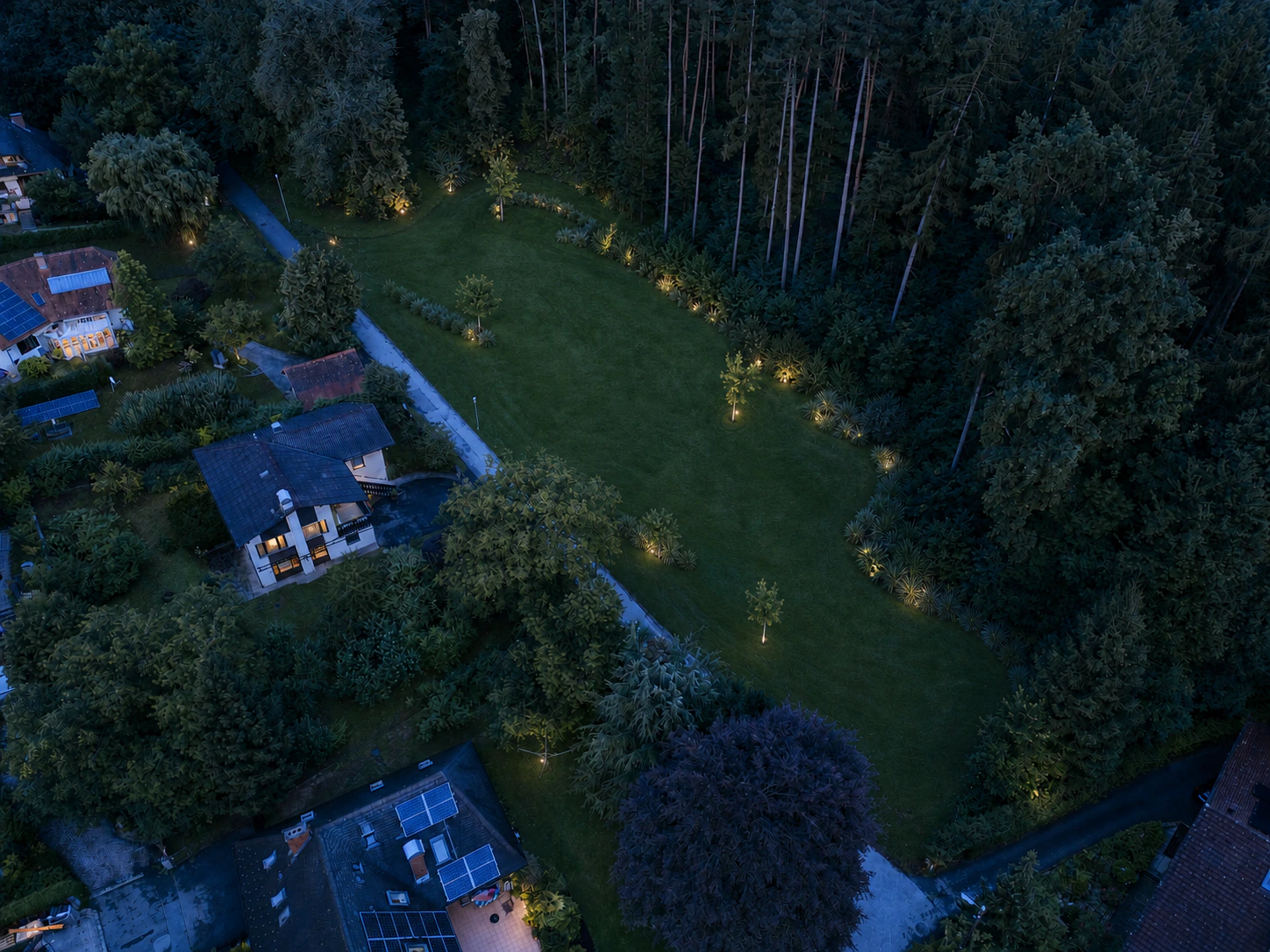 Grundstück zur blauen Stunde mit dezenter Gartenbeleuchtung